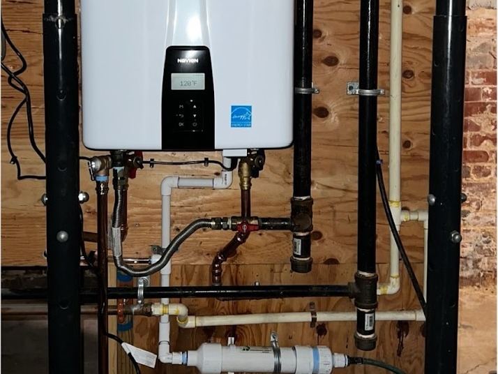 Tankless water heater installed on a basement wall with new supply and gas piping by Platinum Plumbing